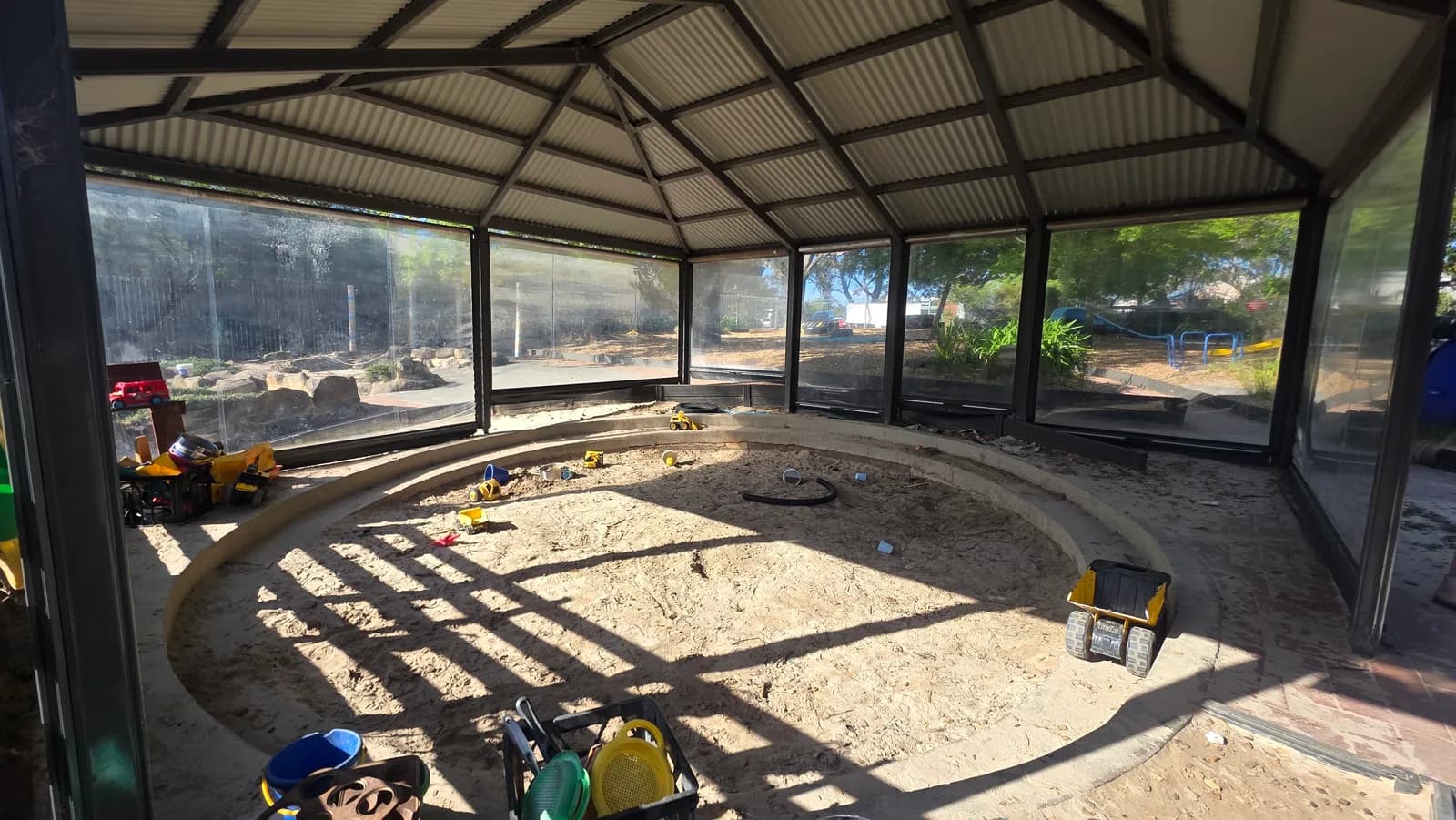 The circular covered sandpit with buckets and small construction toys