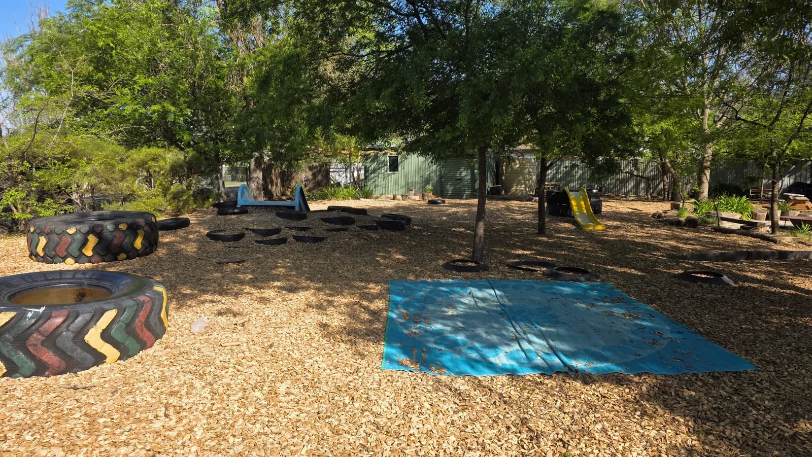 Gum trees, painted tyres and colourful play equipment in the centre yard